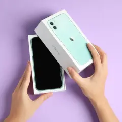 Ręce rozpakowują zielony iPhone 11. Aparat tego modelu pozwala uchwycić każdy piksel z niezwykłą precyzją.