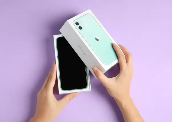 Ręce rozpakowują zielony iPhone 11. Aparat tego modelu pozwala uchwycić każdy piksel z niezwykłą precyzją.